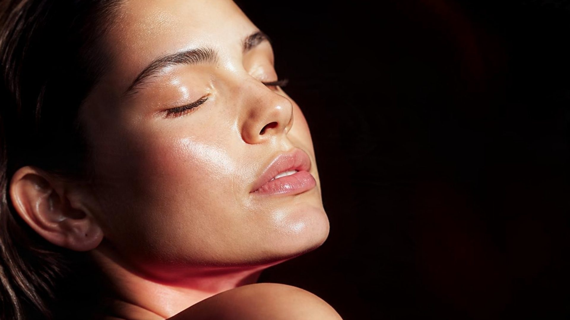 Model with eyes closed, face tilted into warm golden light