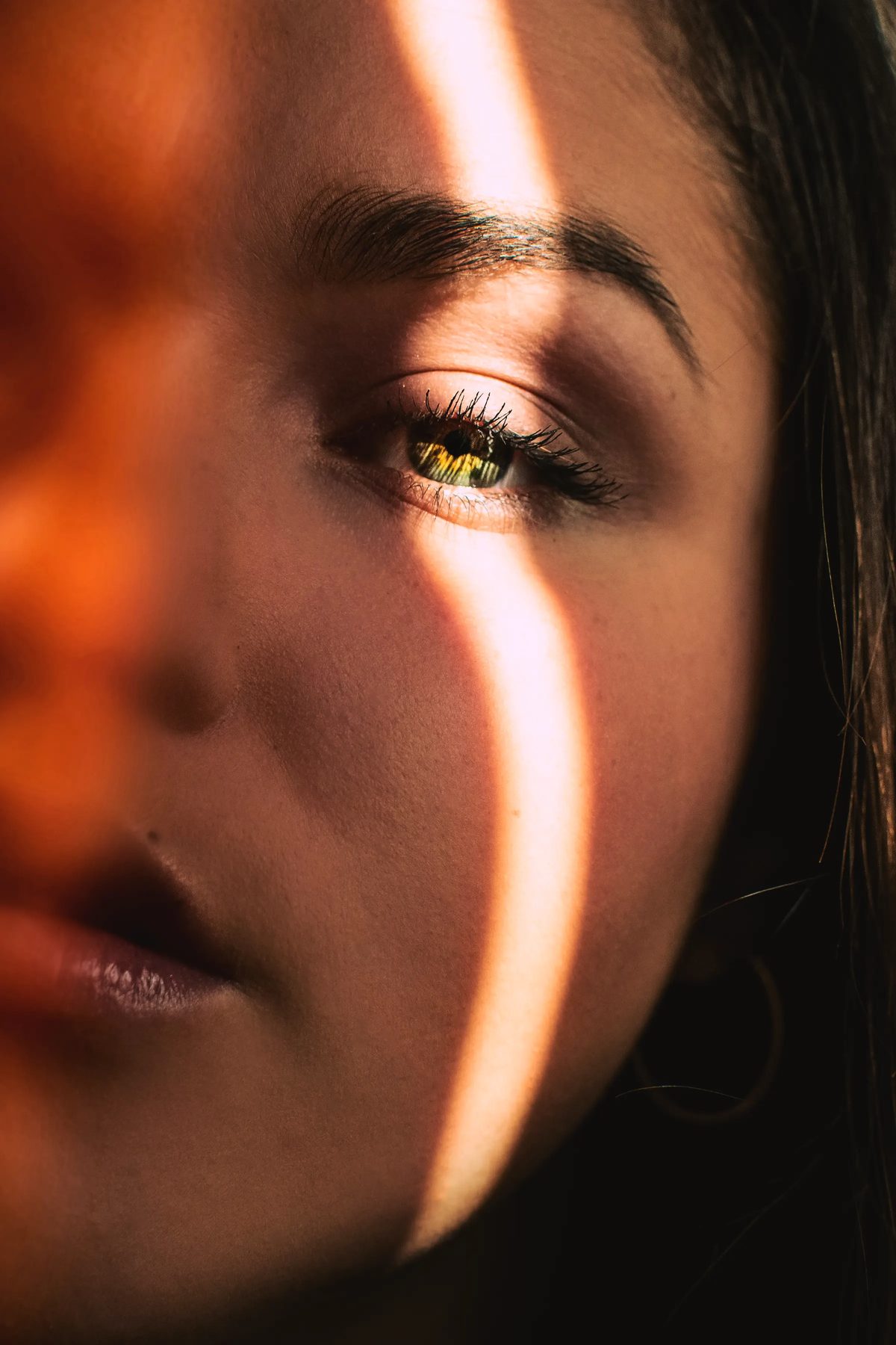 A stripe of warm light across a model’s brow and eye